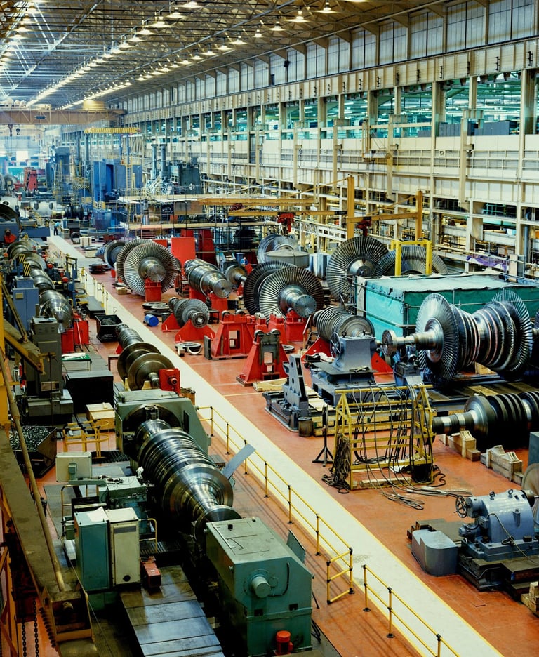 Industrial turbine manufacturing facility with heavy machinery and rotating components on a large assembly floor.