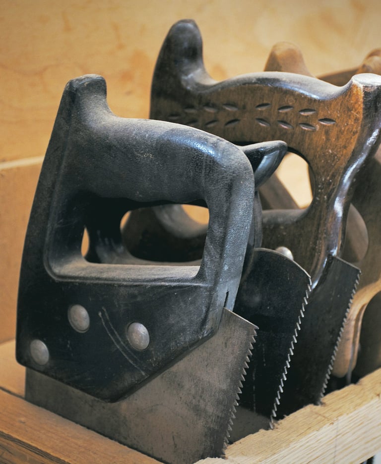 A collection of vintage hand saws with wooden and plastic handles stored in a workshop tool rack.