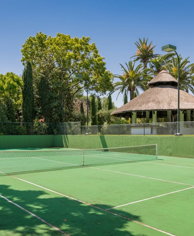 Private tennis court in landscaped Marbella villa grounds