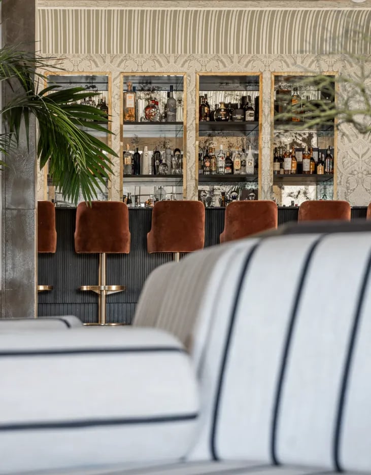 Elegant bar area with velvet stools and display cabinets