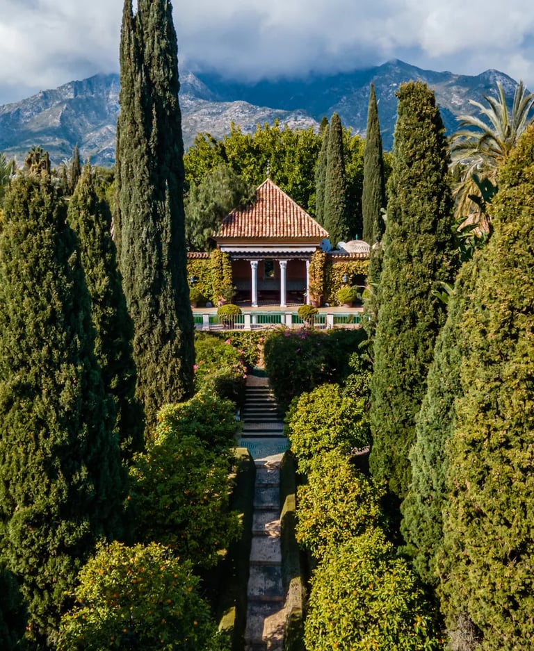Cypress-lined pathway leading to pool pavilion with mountain backdrop