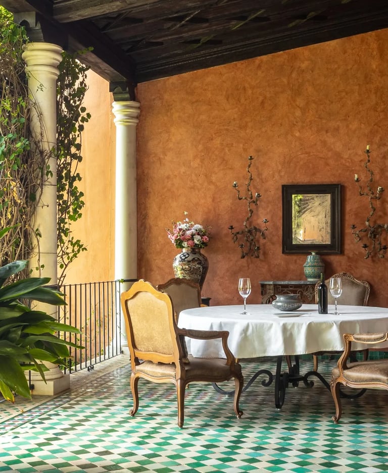Covered terrace dining area with green mosaic floor and terracotta walls