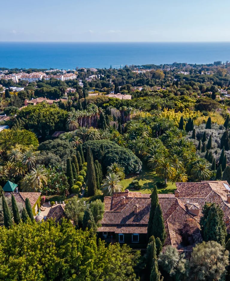 Panoramic aerial view of estate gardens with sea in distance