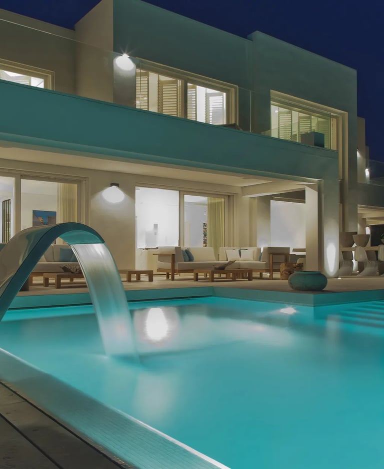 Beachfront villa exterior at night with illuminated pool