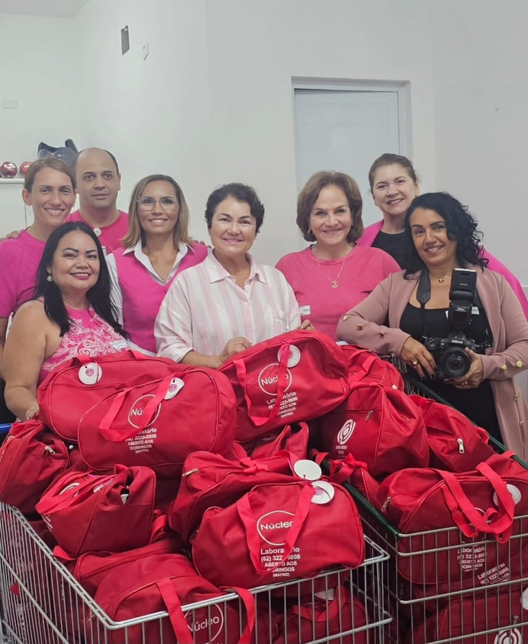Mulheres e homem usando blusas rosas e preta com bolsa vermelhas.
