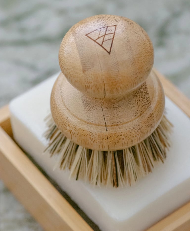 A wooden handled pot scrubber placed on a bar of white soap