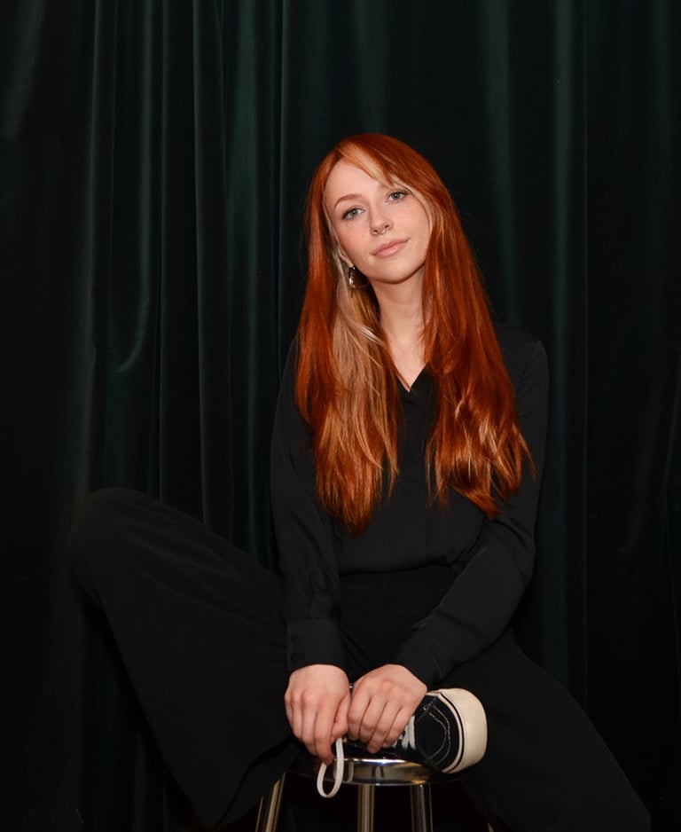 a woman sitting on a stool with a black top, marleenska