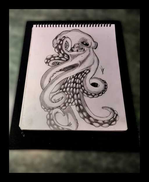Boceto de pulpo dibujado a mano con carbón en un cuaderno de dibujo en espiral, con tentáculos.