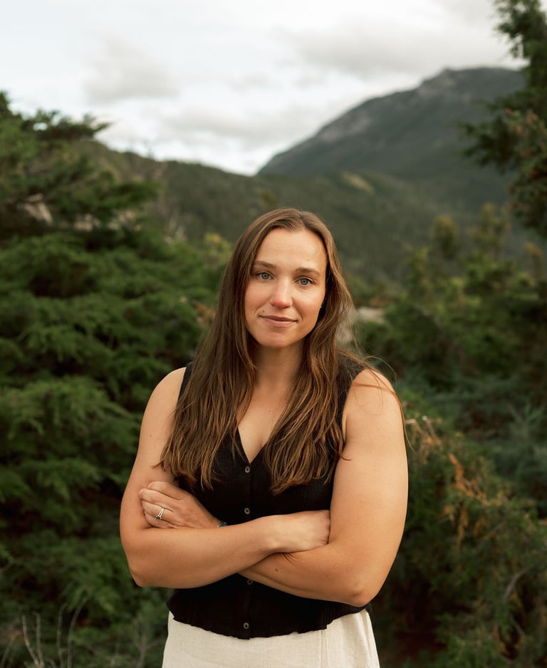 a woman in a white dress standing in front of a mountain