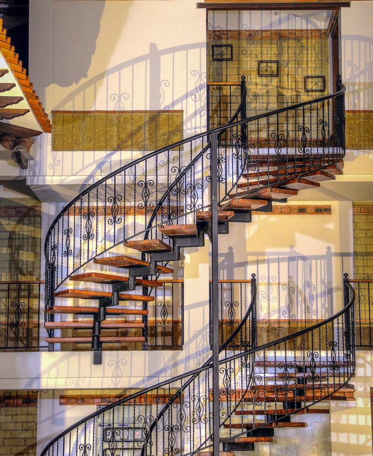 Elegant wrought iron spiral staircase with wooden steps inside a modern rustic home.