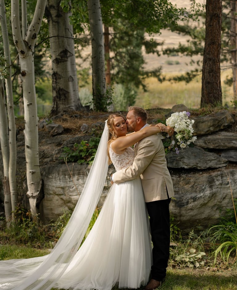 a bride and groom embracing each other in a forest