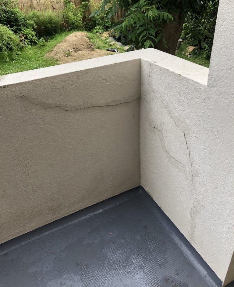 Mur extérieur partiellement réparé avec enduit – fissures comblées avant finition.