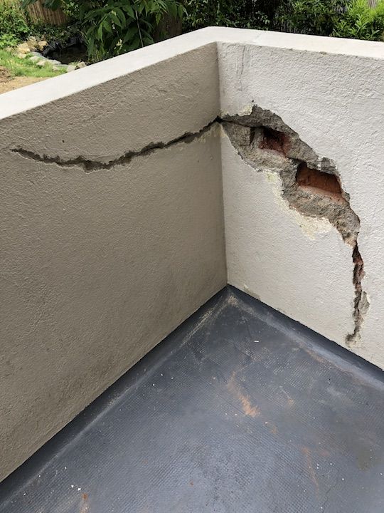 Mur de balcon fissuré avec éclatement partiel du crépi – état initial avant réparation.