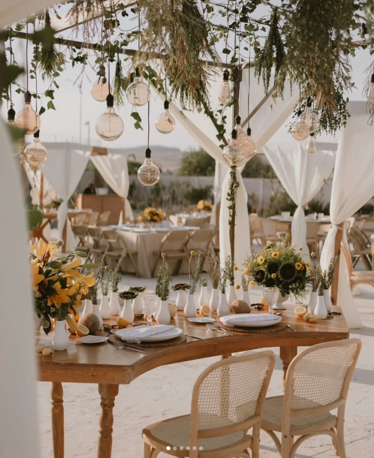 Mesa de boda al aire libre con decoración blanca y girasoles.