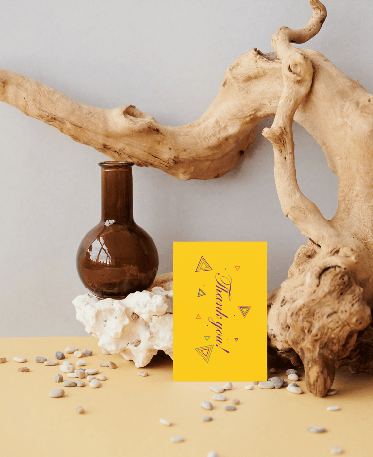 Yellow thank you card with geometric designs on a rustic display with driftwood and a brown glass vase.