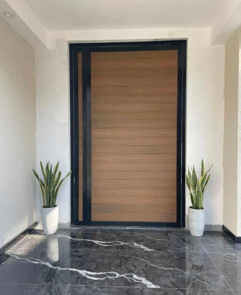 Modern villa main entrance door with wood-grain aluminum finish and black frame.