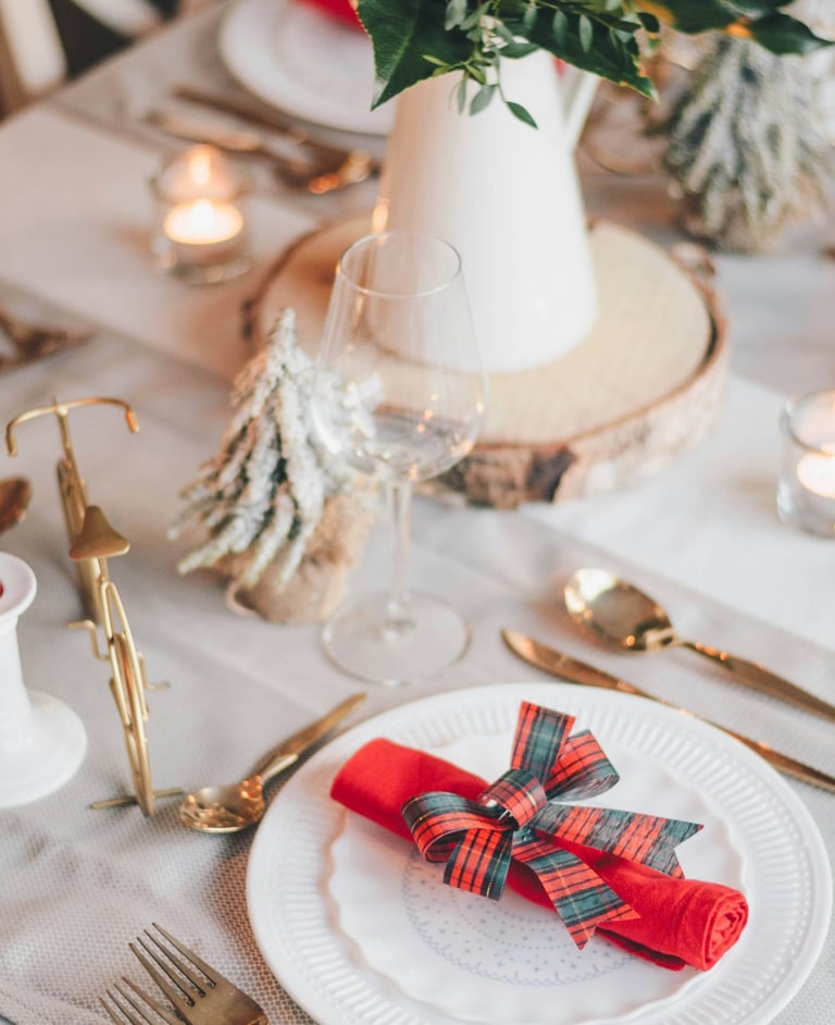 a table setting with a red napkin and a vase with flowers