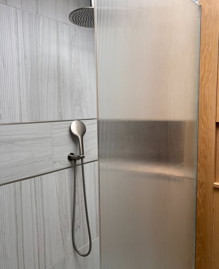 fluted tiles and shower screen with brushed stainless shower head