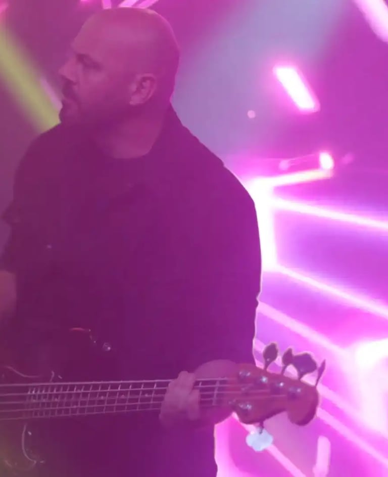 a man with a guitar and a guitar in front of a purple light