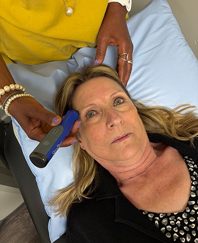 older woman laying on a doctors table receiving microneedling treatment
