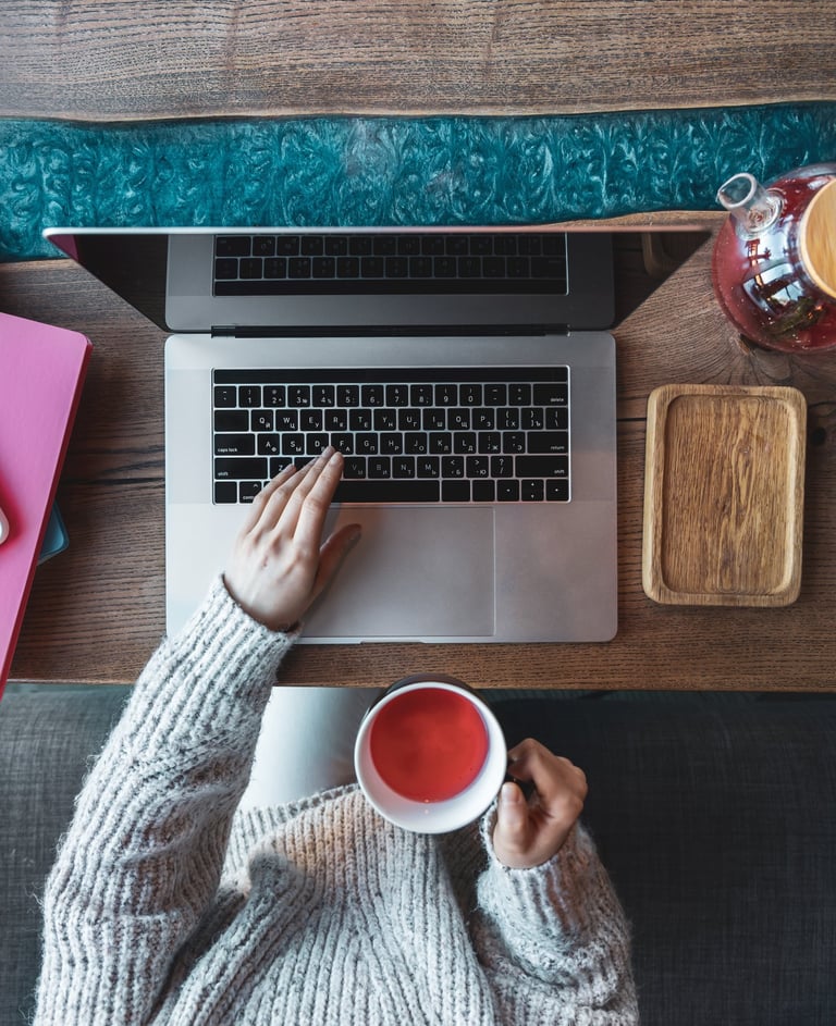 Persona trabajando en laptop con una taza de té, representando home office,