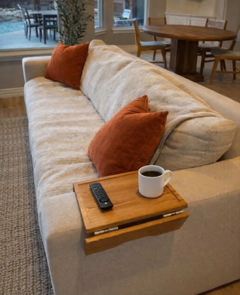 Wooden sofa arm tray table holding coffee and remote