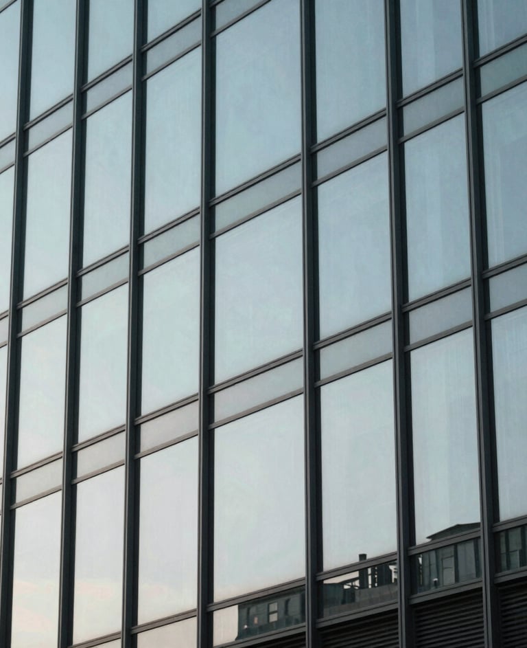 Clean street photography of a modern glass building reflecting a pale silver blue sky, minimalistic composition with sharp geometric lines, International / Western.