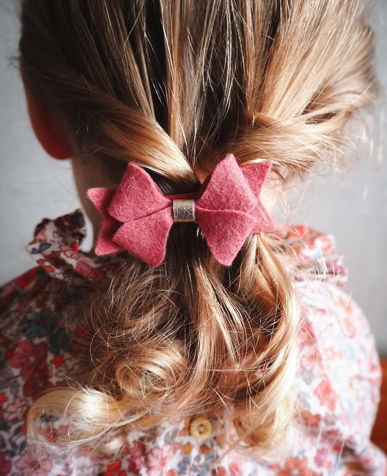 kokarda z koralowego filcu zapięta na włosach dziewczynki z jasnymi włosami
