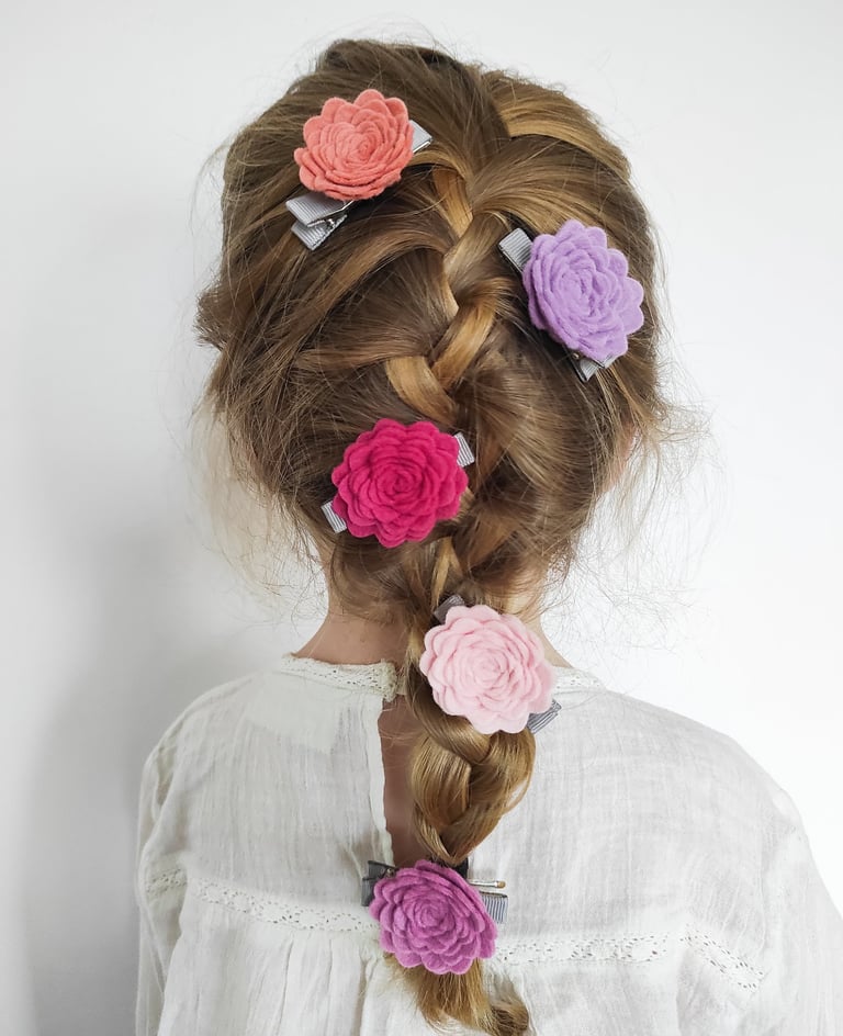 dziewczynka z warkoczem, w który wpięte są spinki w kształcie róż