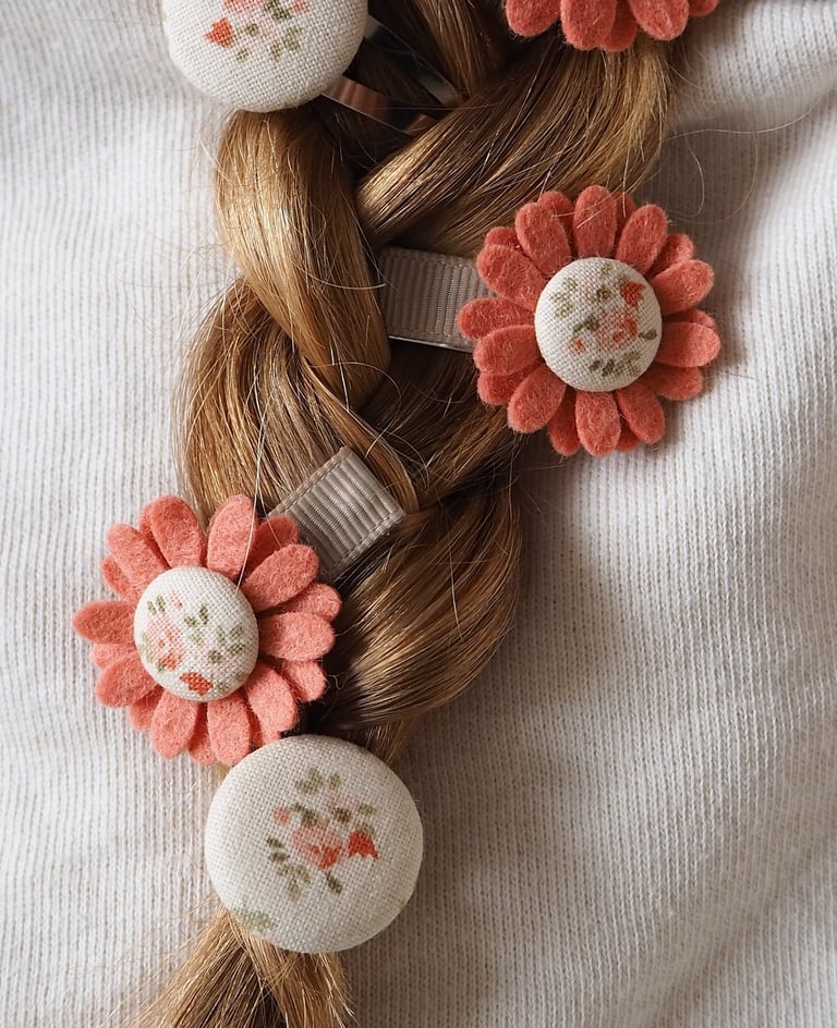 warkocz z włosów ozdobionymi spinkami do włosów w kwiaty