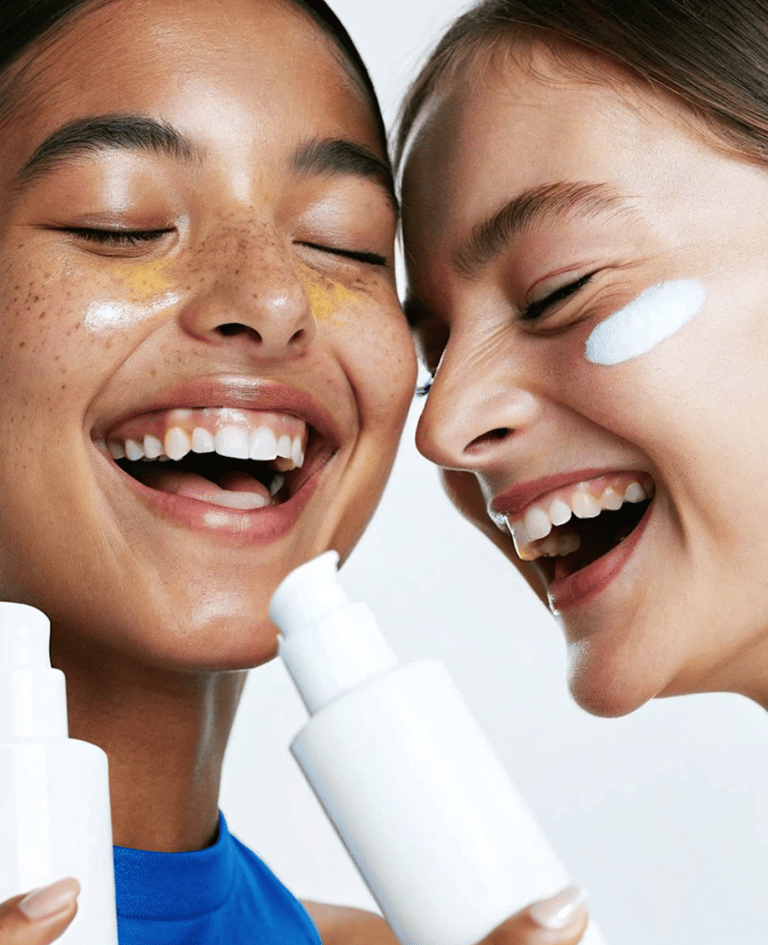 two girls laughing holding bottles of skincare
