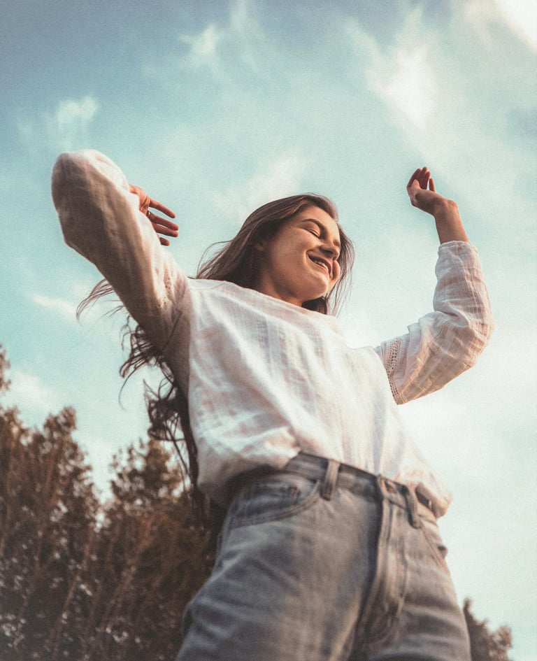 Femme souriante levant les bras au ciel, symbole de transformation réussie
