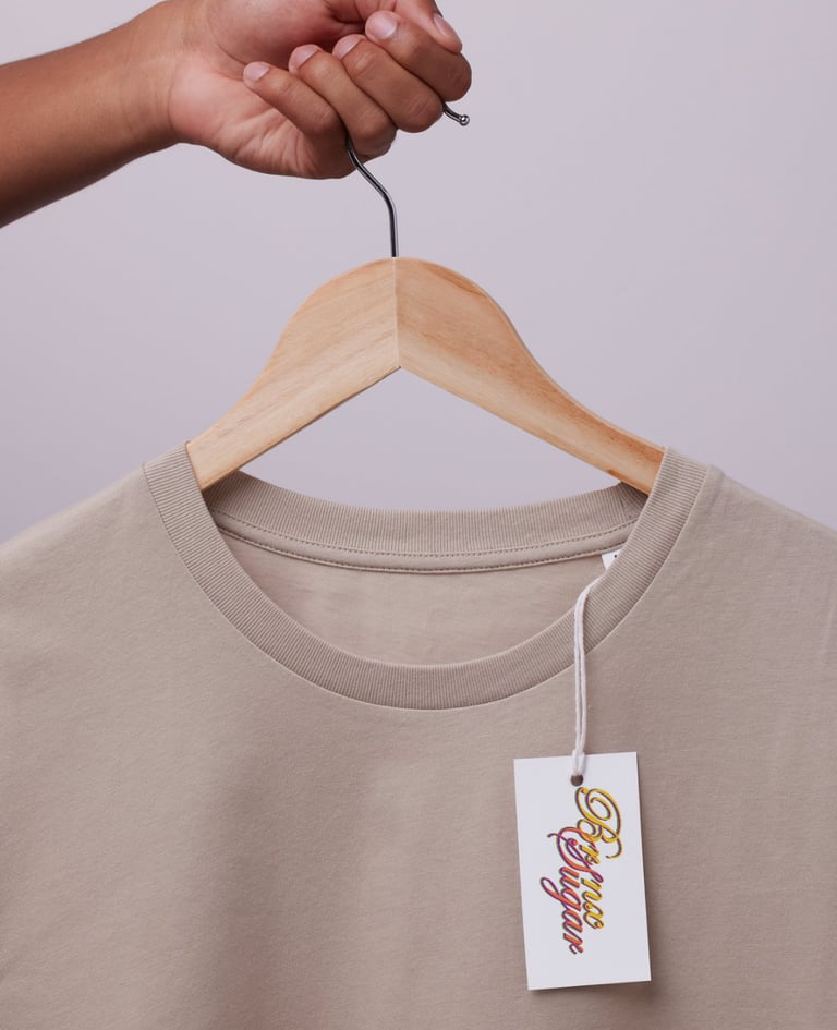 Close-up of a beige crew neck cotton t-shirt on a wooden hanger with a brand logo hang tag.