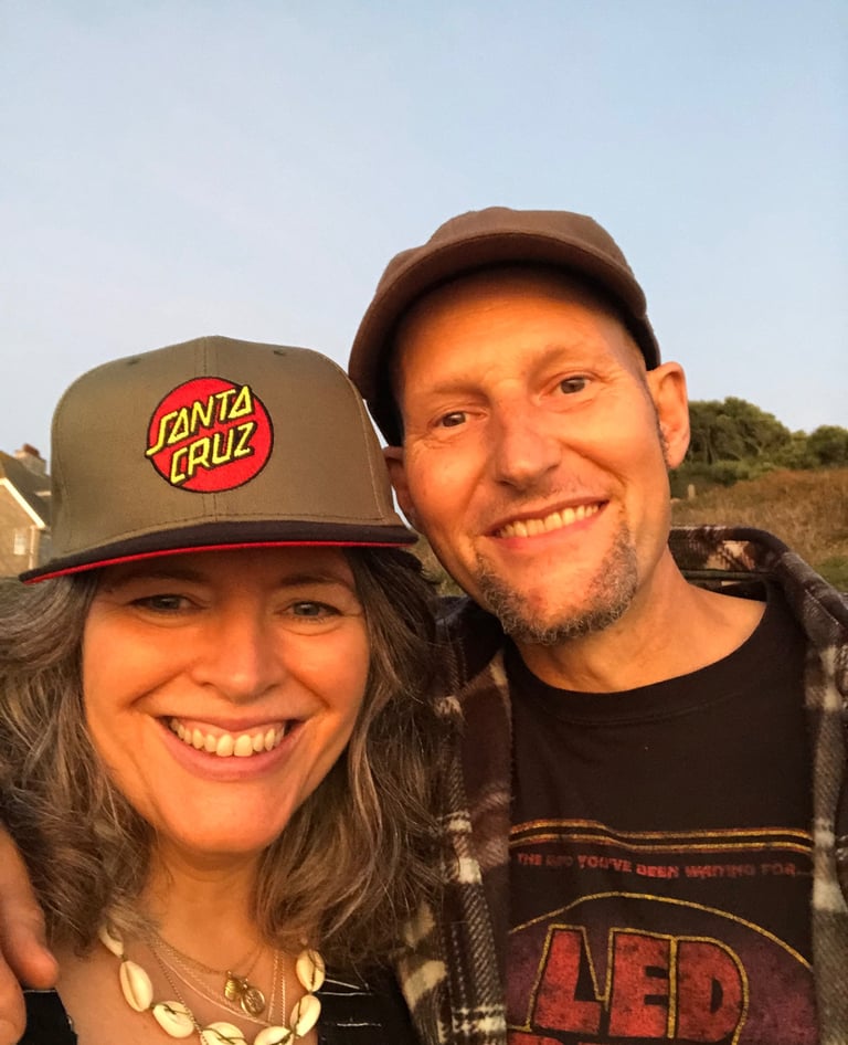 smiling couple wearing hats taken at sunset