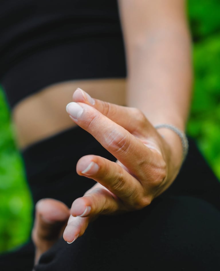 Close-up of fingers in meditation mudra before lush green background, guided meditation