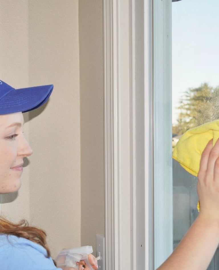 Lady cleaner from Chez Cleaning Services cleaning a glass door of a house with a rag