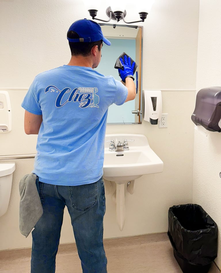 Janitor from Chez Cleaning Services cleaning a mirror in a bathroom