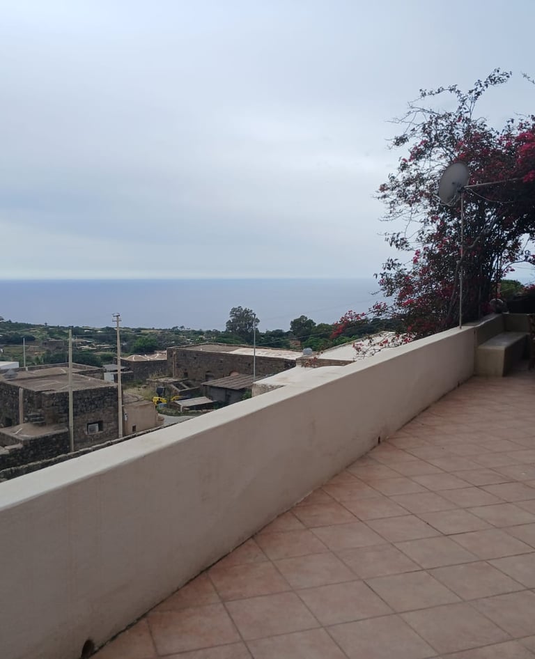 Panoramic terrace of dammuso in Rekhale with flowering pergola and sea view