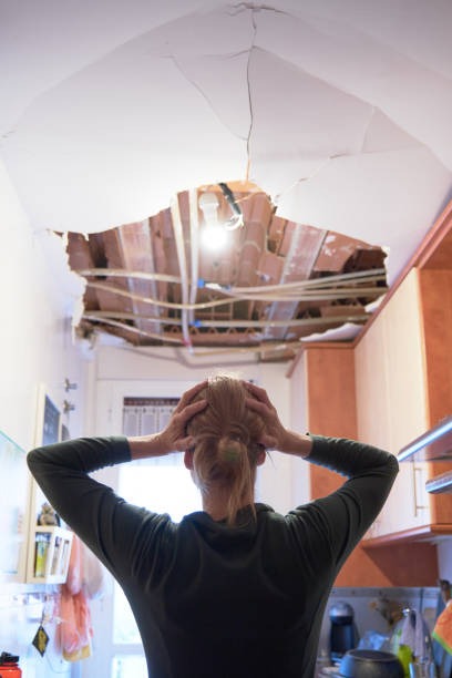 woman holding her head looking at damage to house from a leak