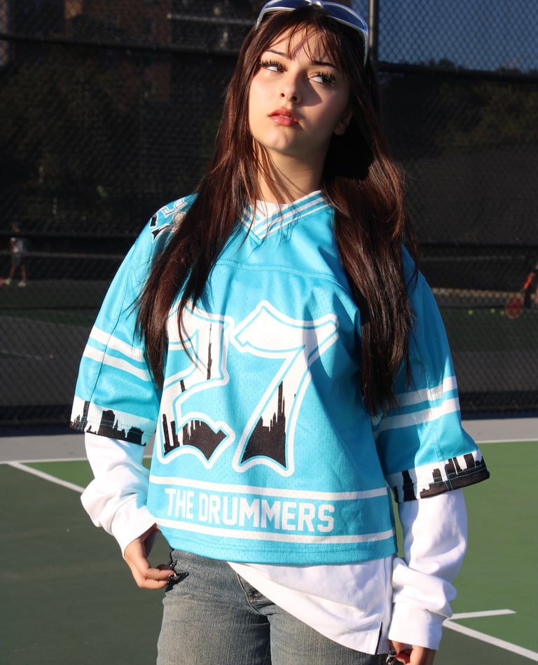 a woman in a blue shirt and jeans standing on a tennis court