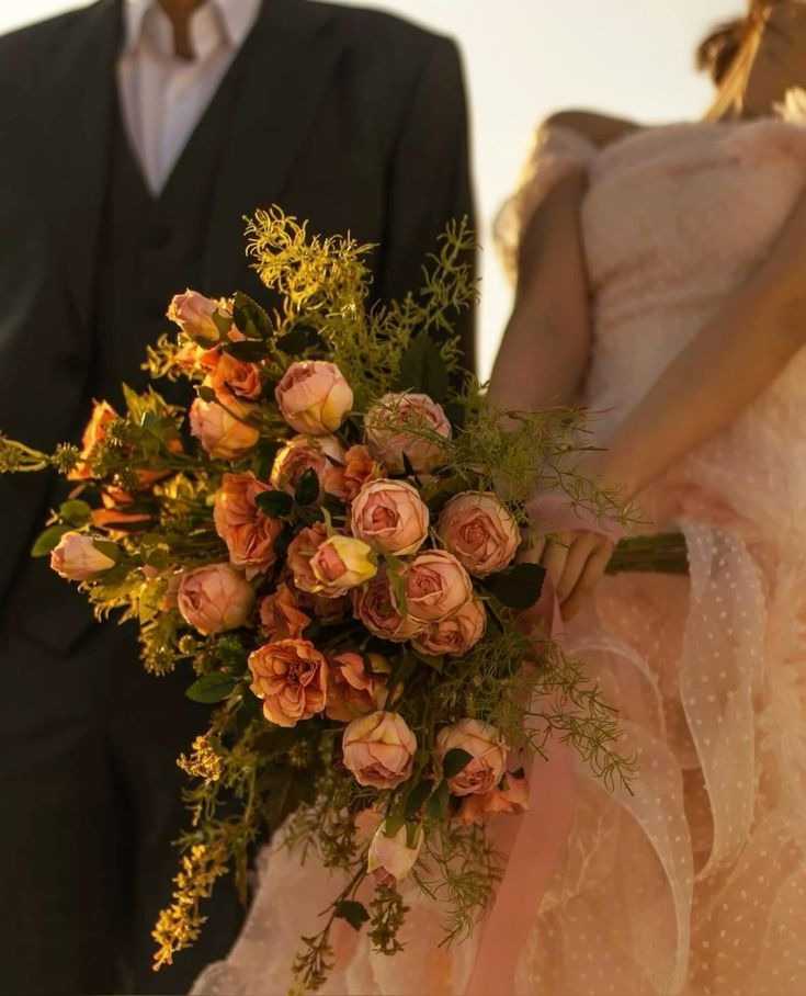 Novia con ramo de rosas en tonos durazno y verde.