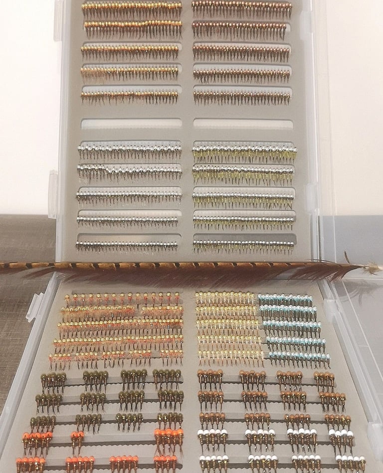fly fishing box filled with organized rows of tungsten beadhead nymphs and midges.