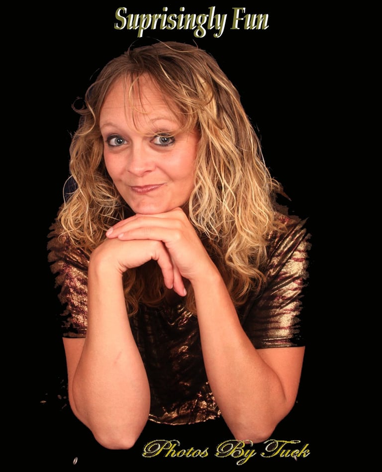 A blonde woman with curly hair smiles in a studio portrait against a black background.