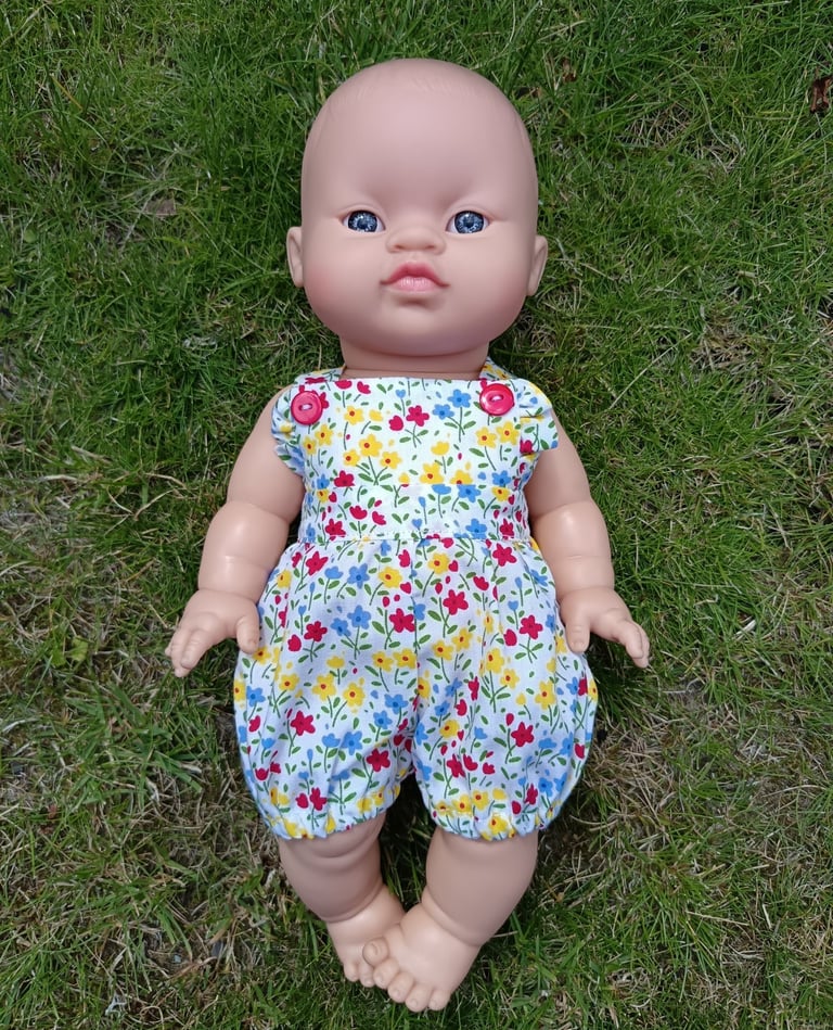 Minikane doll Koko dressed in short floral dungarees