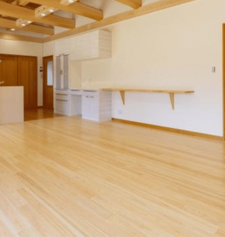 Empty modern open concept living room featuring light hinoki flooring and exposed ceiling beams.