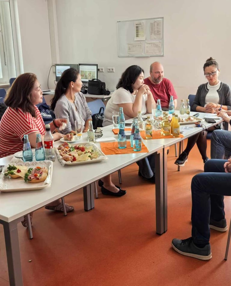 Diverse colleagues sharing lunch and snacks at a business meeting table in an office.