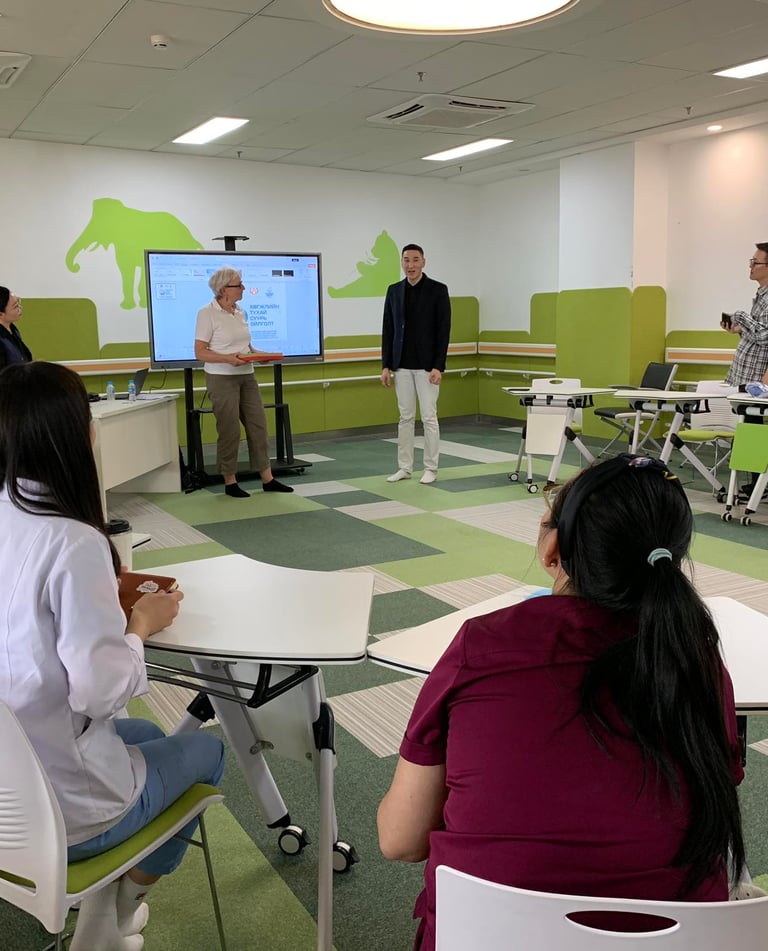 A modern healthcare training room where staff attend a digital presentation on a smart screen.