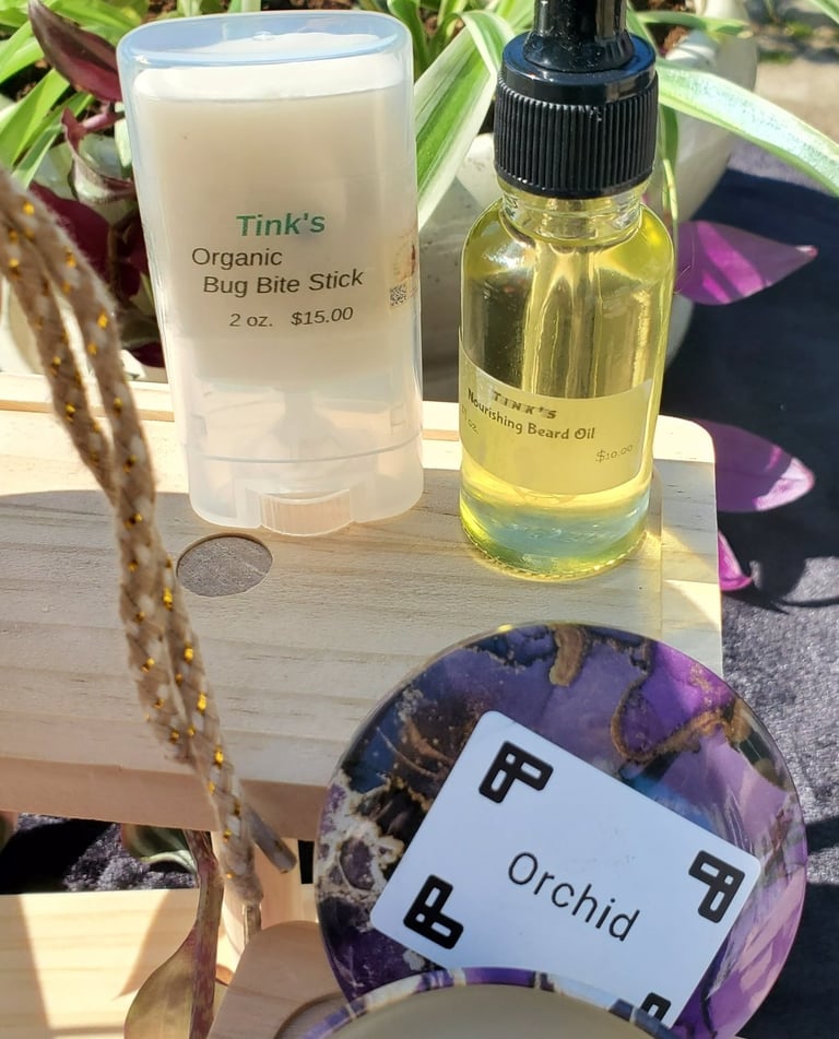 Handmade organic bug bite stick, nourishing beard oil, and an orchid scented candle on display