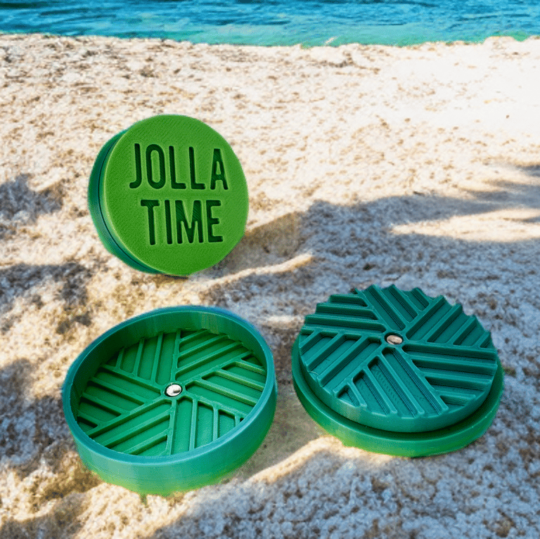 grinder color verde sfumato verso il blu, posato sulla spiaggia