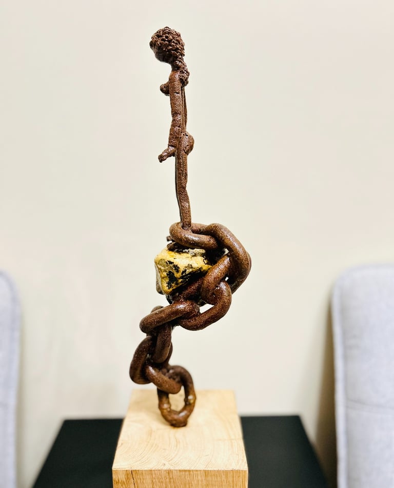 Iron sculpture with stone on wooden pedestal